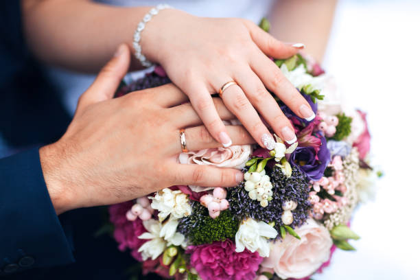 istock Bride hands with ring and wedding bouquet of flowers 668001758