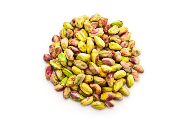 Front view of peeled pistachio nuts heap shot from above isolated on reflective white background. DSRL studio photo taken with Canon EOS 5D Mk II and Canon EF 100mm f/2.8L Macro IS USM
