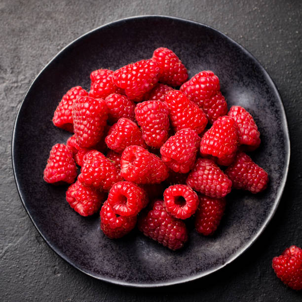 istock Fresh raspberries on a black bowl Slate background. Top view. 668023252