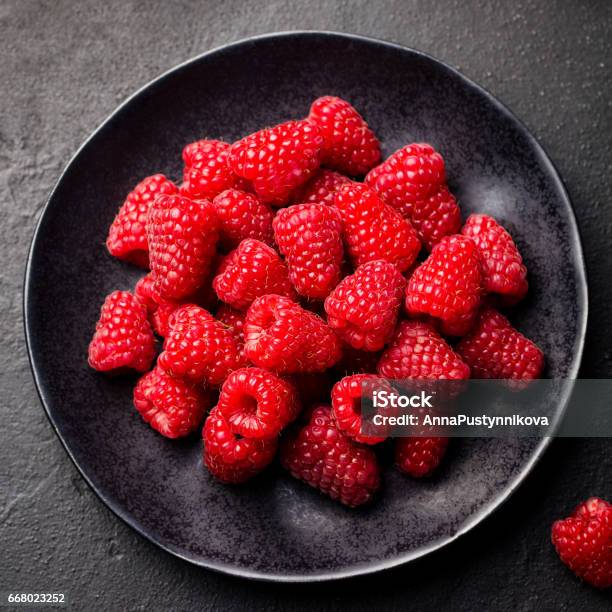 Fresh Raspberries On A Black Bowl Slate Background Top View Stock Photo - Download Image Now