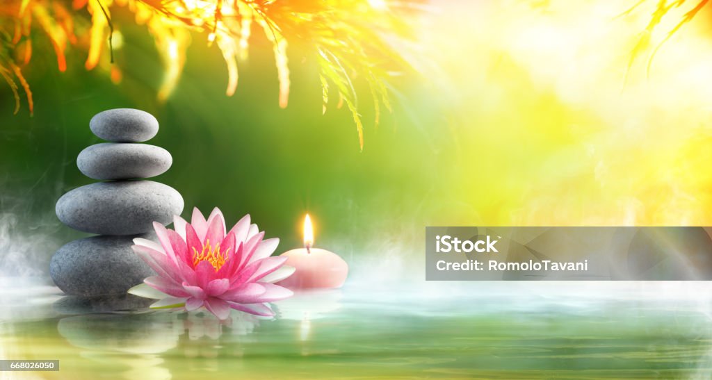 Spa - Relaxation With Massage Stones And Waterlily In Water Spa still life - Stack Of Stones With Candle and Lotus In Pond Zen-like Stock Photo