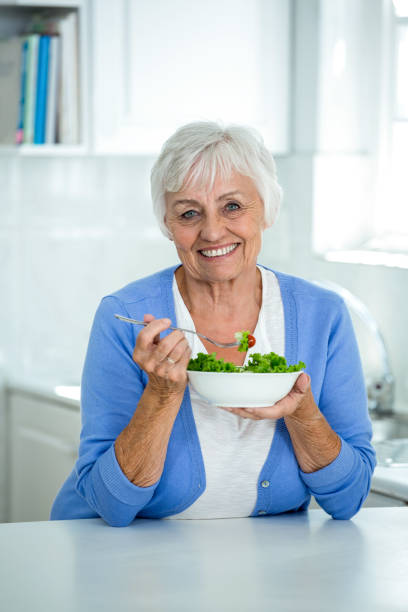 istock Senior woman eating salad in kitchen 668027590