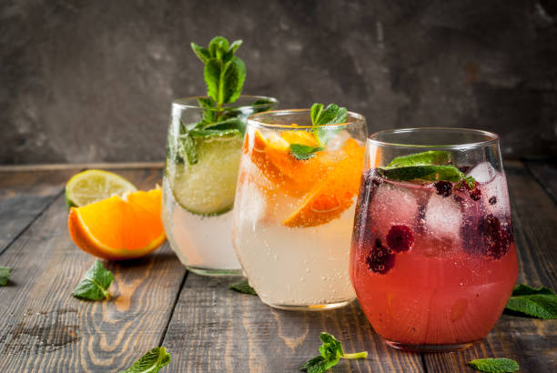Set of three kinds of gin tonic Selection of three kinds of gin tonic: with blackberries, with orange, with lime and mint leaves. In glasses on a rustic wooden background. Copy space cold drink stock pictures, royalty-free photos & images