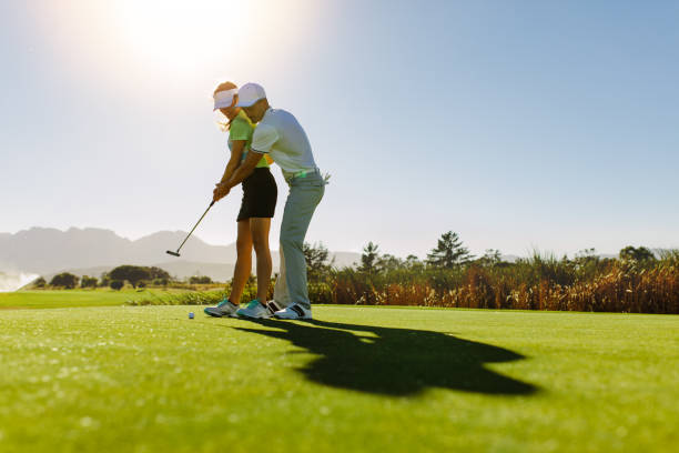 man teaching woman to play golf on field - golf expertise professional sport men imagens e fotografias de stock