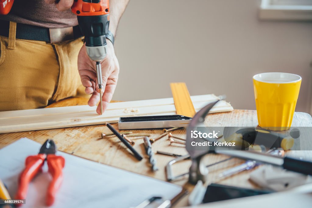 Man Screwing A Screw Into Wood Man Screwing A Screw Into Wood with cordless drill Adult Stock Photo