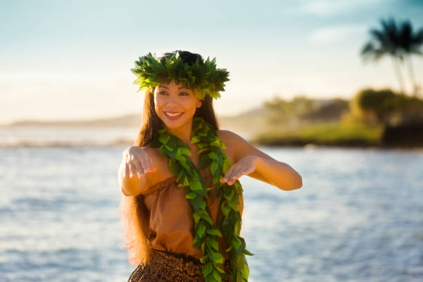 Portrait of Hawaiian Hula Dancer Dancing on the Beach A beautiful Hawaiian Hula dancer dancing on the beach of the tropical Hawaiian islands. She is wearing a traditional Hula dance dress with a lei and a head dress. Photographed in vertical format with copy space in Kauai, Hawaii. polynesia photos stock pictures, royalty-free photos & images