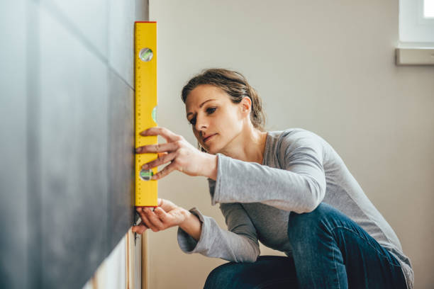 Woman using leveling tool Woman wearing grey shirt using leveling tool at home measuring a room stock pictures, royalty-free photos & images