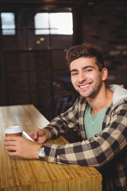 istock Smiling hipster holding smartphone and take-away cup 668053046