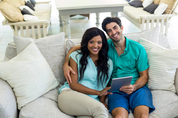 istock Portrait of young couple sitting on sofa and using digital tablet 668054500