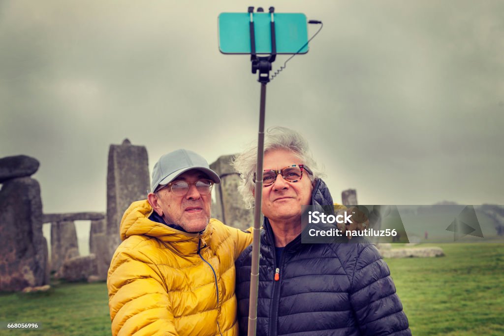 mature men friends take a selfie in the Stonehenge archaeological site mature men friends take a selfie in the Stonehenge archaeological site - concept of active senior who travel and have fun 60-69 Years Stock Photo