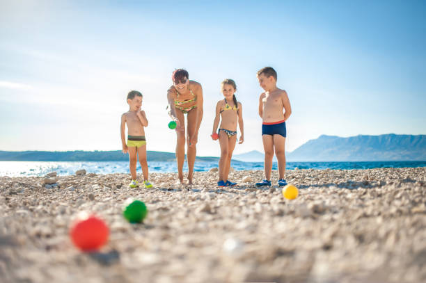 mutter spielen boccia mit kindern am strand - pétanque stock-fotos und bilder