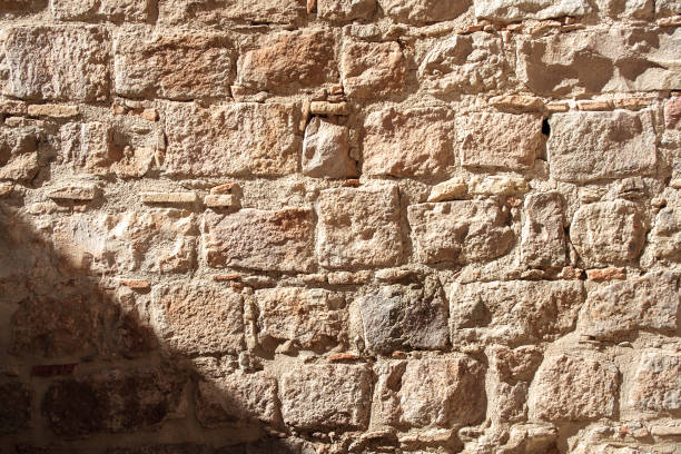 istock medieval stone wall of old building in sunny day With a shadow falling on it 668064076