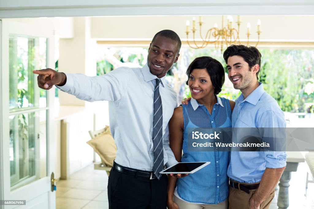 Real estate agent showing the house to couple Real estate agent pointing while showing the house to couple Real Estate Agent Stock Photo