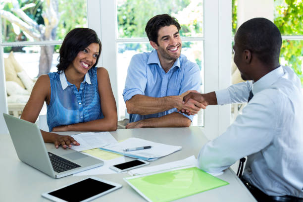 istock Happy couple shaking hands with real estate agent 668067508