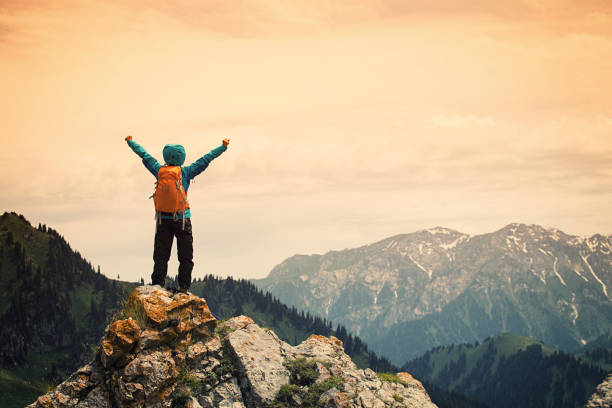 istock successful young woman backpacker open arms on mountain peak 668067710