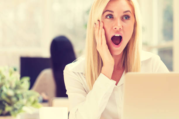istock Surprised young woman sitting at her desk 668070974