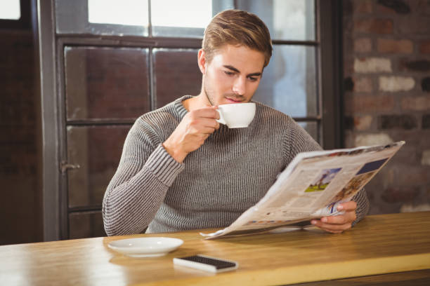istock Handsome man drinking coffee and reading newspaper 668073942