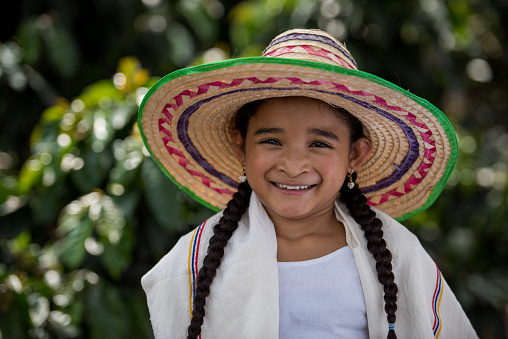 Portrait of a happy Colombian girl at a coffee farm looking at the camera smiling