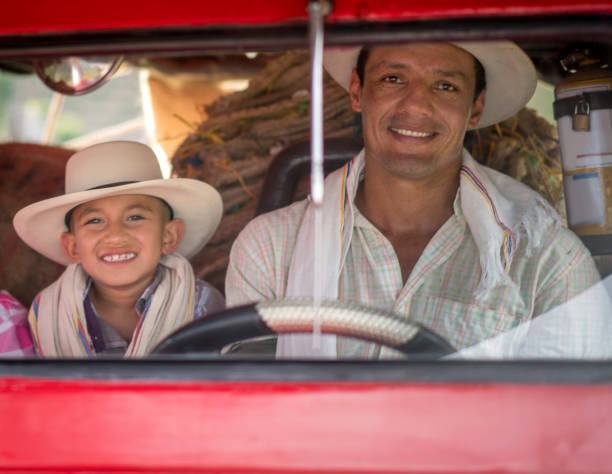 Portrait of a Colombian father and son driving a car at the farm and looking happy - farming concepts