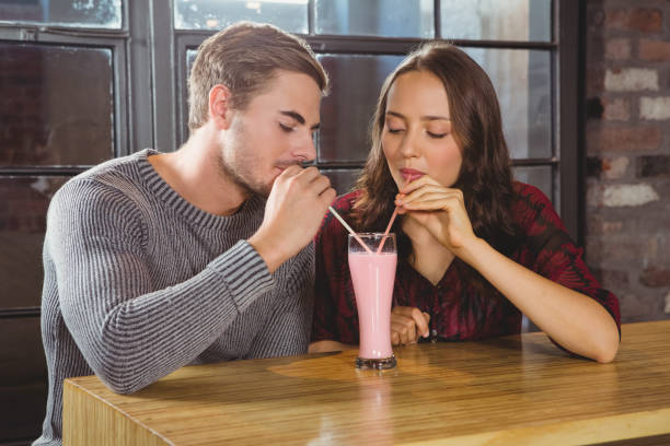 istock Smiling friends sharing smoothie and drinking through straws 668076868