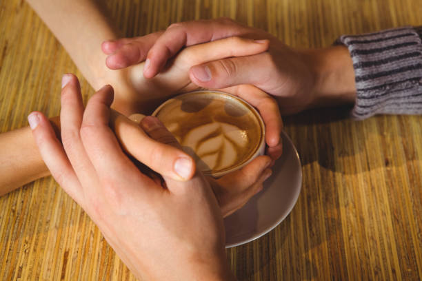 istock Couple holding hands around cappuccino with coffee art 668076922