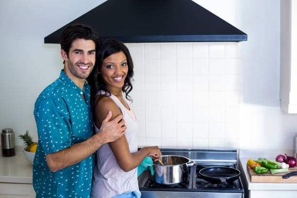 istock Man embracing woman while cooking in kitchen 668080912