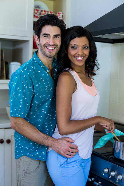 istock Man embracing woman while cooking in kitchen 668080944
