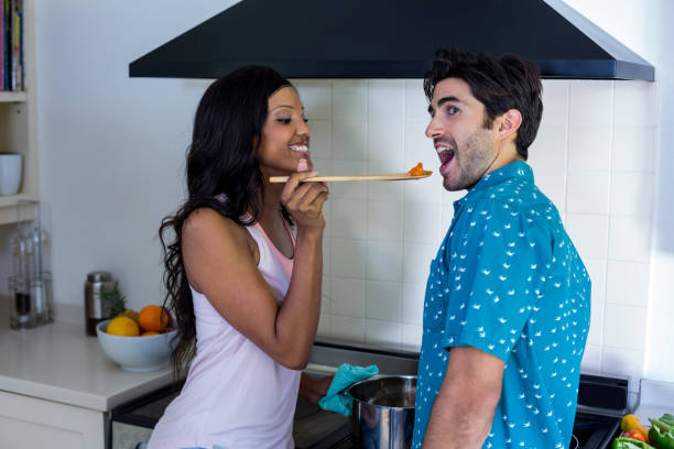 istock Woman feeding man while cooking in kitchen 668082996