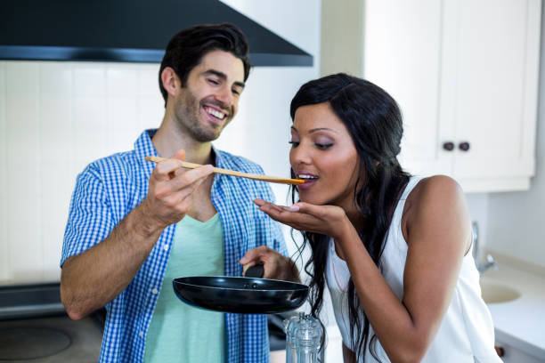 istock Man feeding woman while cooking in kitchen 668083026