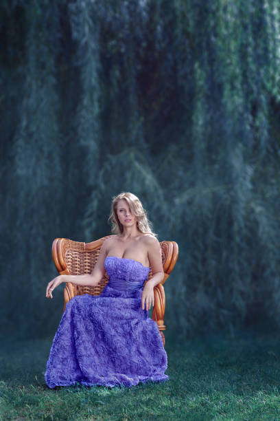 Beautiful young blonde woman in luxury dress posing in front of magical forest