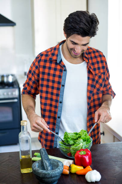 istock Portrait of man mixing a salad in kitchen 668083688