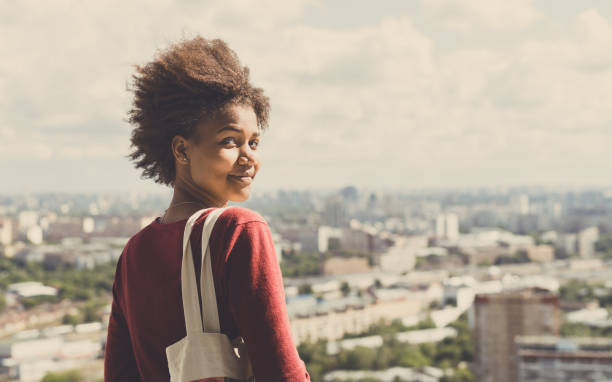istock Curly mixed girl on balcony with cityscape behind 668090174