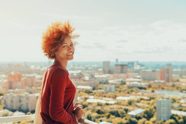 istock Curly mixed girl on balcony with cityscape behind 668090246