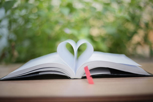 istock Open book on wooden table on natural background. Heart book page , blurry and soft focus 668090672