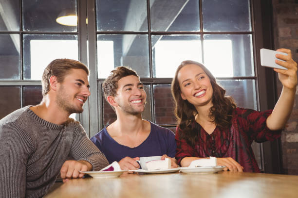istock Smiling friends having coffee and taking selfies 668090702
