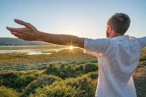 Young man arms outstretched by the wetlands. Shot in Knysna, South Africa.