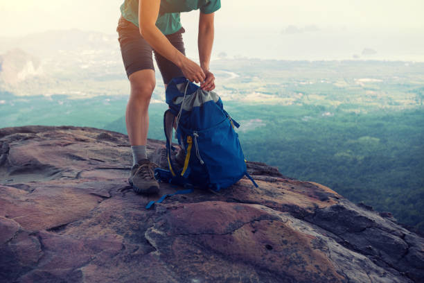 successful woman hiker packing the backpack hiking on mountain peak