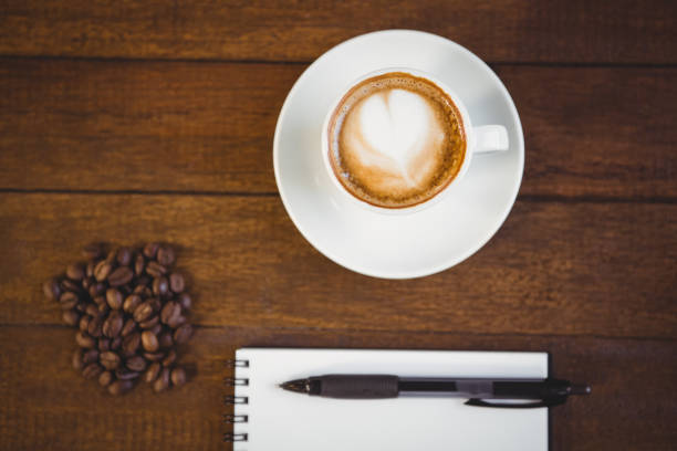 istock Cup of cappuccino and notepad with pen 668103716
