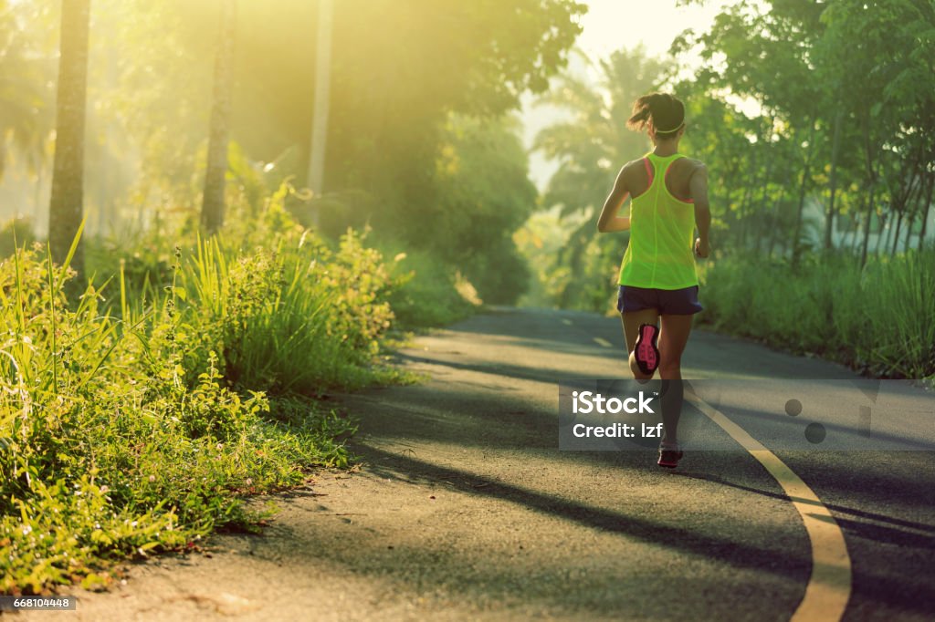 Young fitness woman running on morning tropical forest trail Active Lifestyle Stock Photo