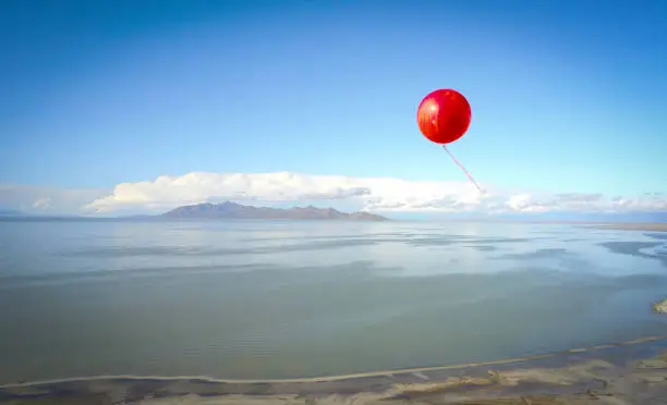 Lone red balloon floating high over the great salt lake