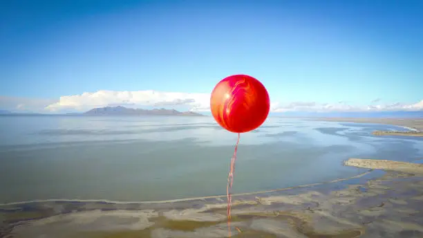 Lone red balloon floating high over the great salt lake