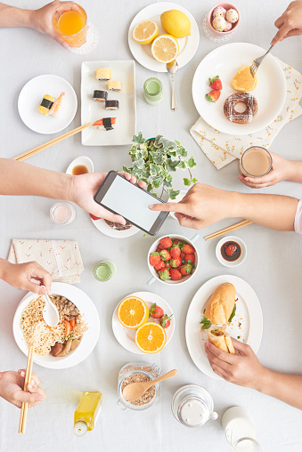 People passing smartphone when eating together, view from the top