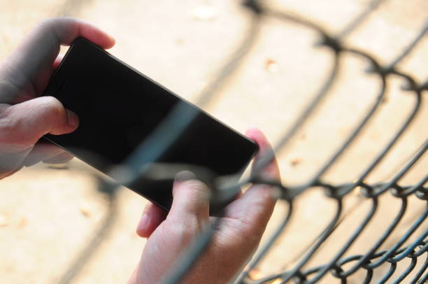 Playing mobile phone in rusty steel wire mesh fence restricted area