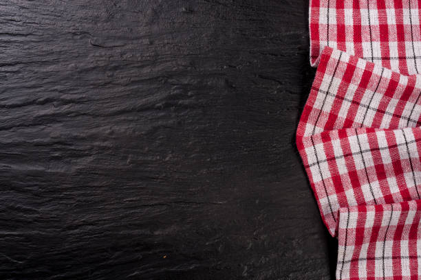 istock Red checkered tablecloth on a dark stone background with copy space for your text. Top view 668143534