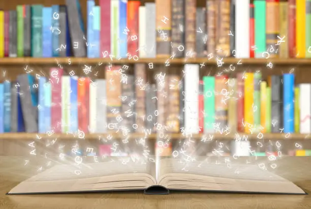 Open magic book with magic lights on a bookshelf