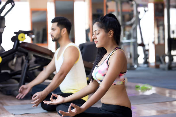 Fit young couple meditating Fit young couple sitting in a lotus position and meditating at yoga class yoga studio photos stock pictures, royalty-free photos & images