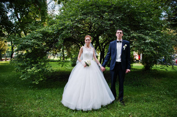 istock exciting elegant wedding couple walking at park in love 668157948