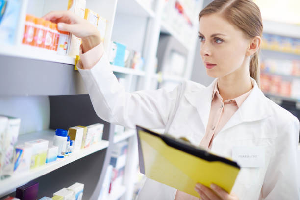 istock Young pharmacist looking at shelf of pills 668167976