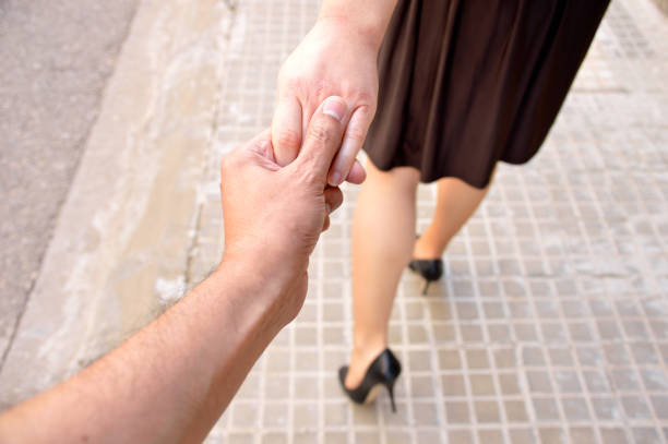 pretty woman leading her husband by the hand while walking on the city together wearing stilettos