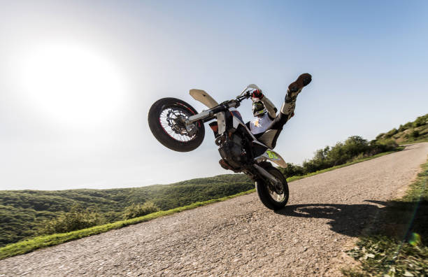 istock Below view of motorcyclist balancing on back wheel. 668178858